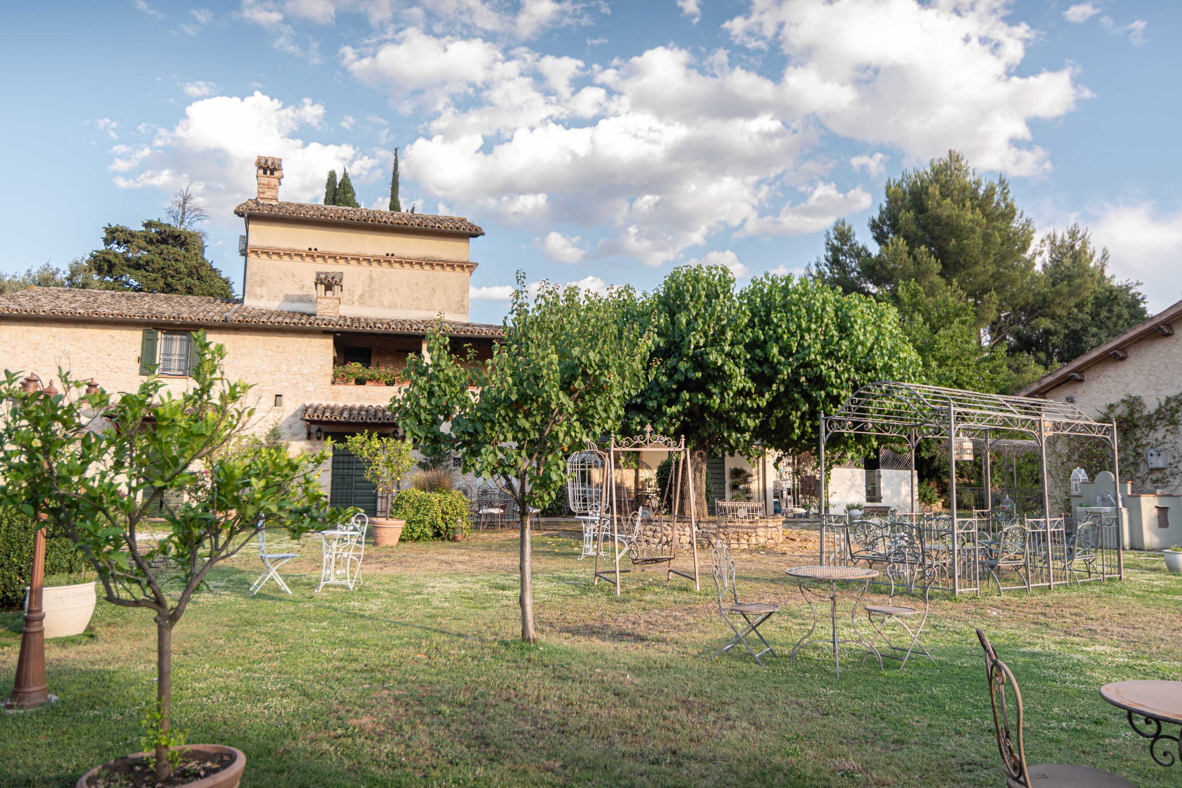Un patio con una pérgola, mobiliario exterior y un edificio con techo de tejas.