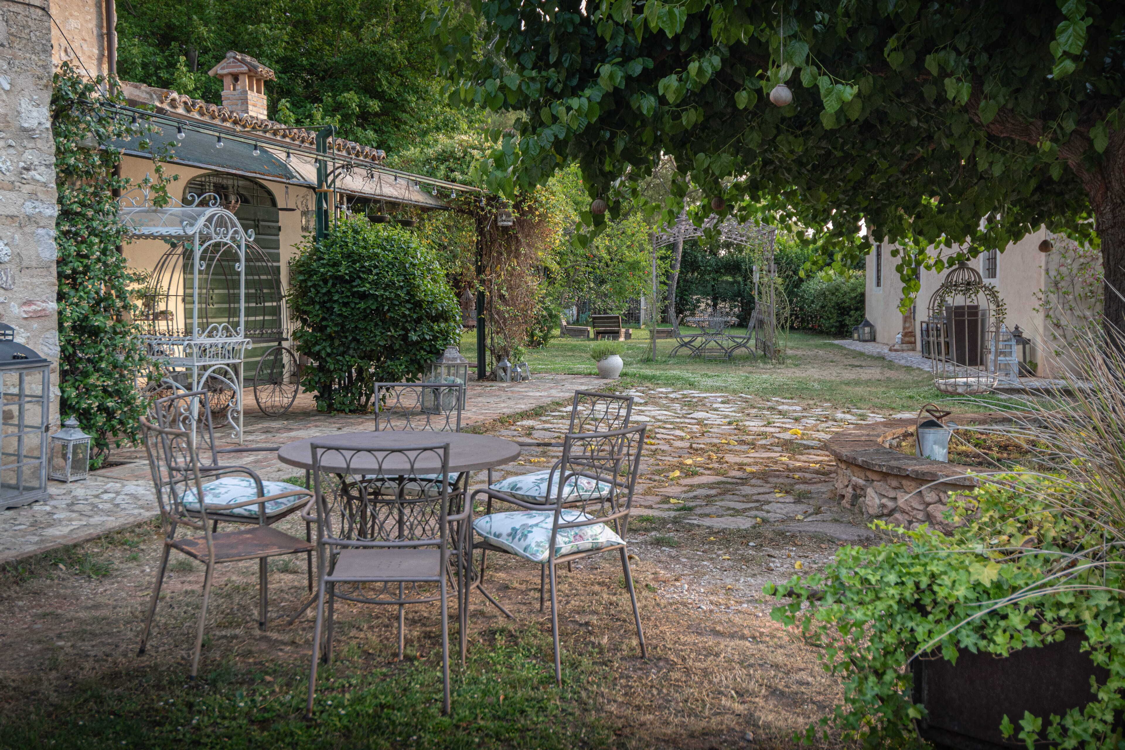 Ein Innenhof mit Steinboden, Metallstühlen, einem Tisch und einer Pergola.