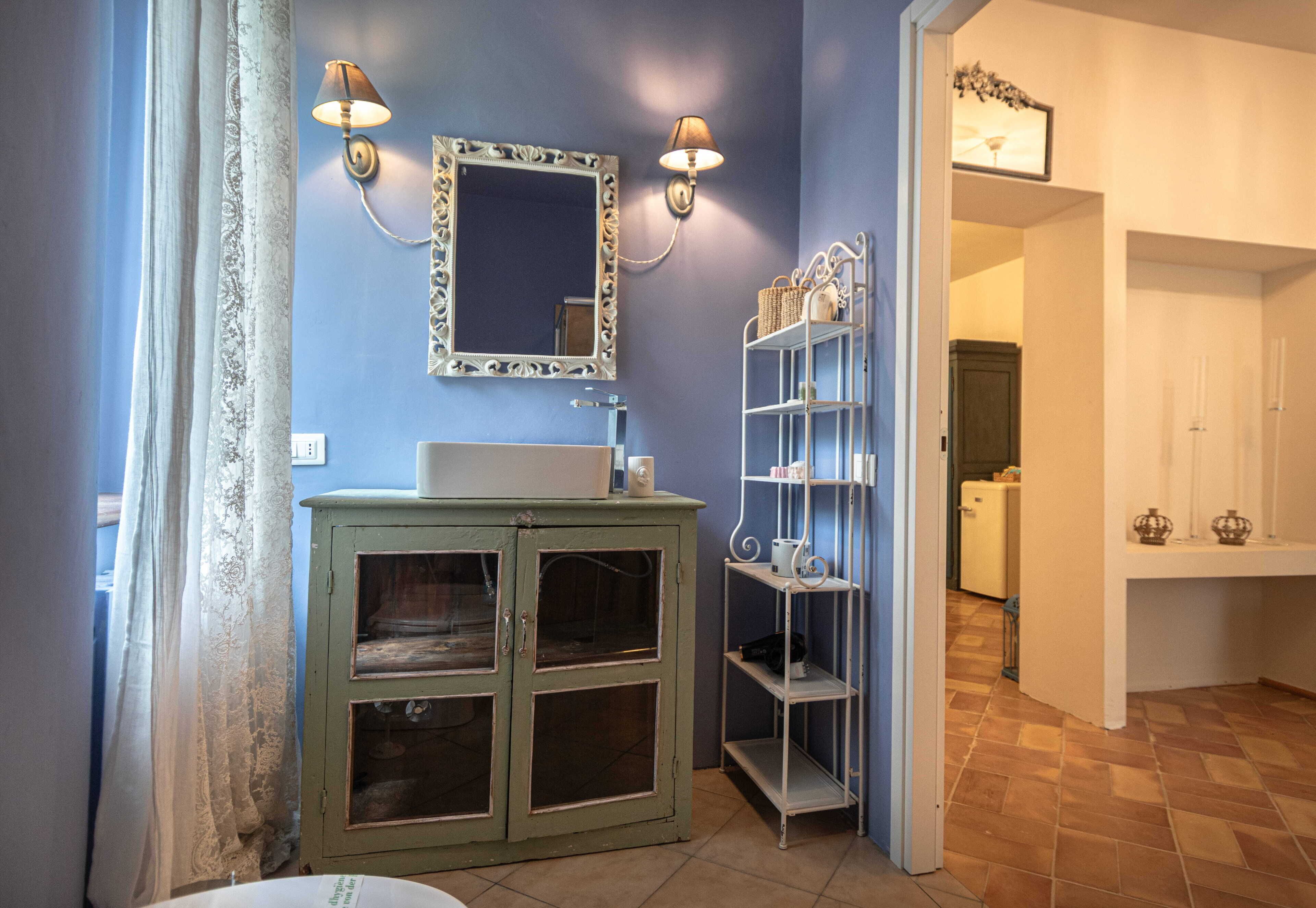 A bathroom with a sink, mirror, and shelves.