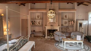 Una habitación con cama con dosel, chimenea, candelabro y una mesa de comedor con un menú.
