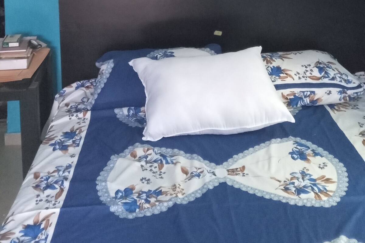 A bed with a floral bedspread, a white pillow, and a dark headboard.