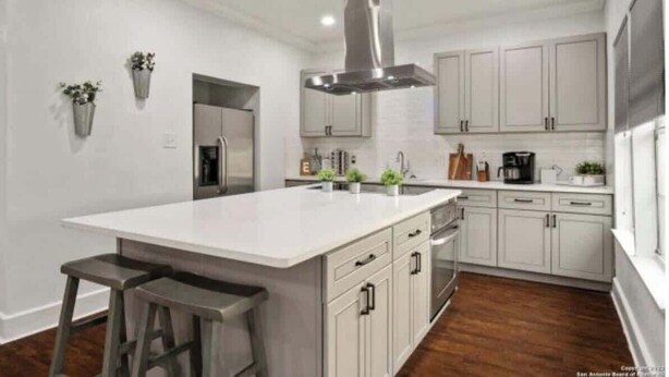 Una cucina moderna con una grande isola, mobili bianchi ed elettrodomestici in acciaio inossidabile.