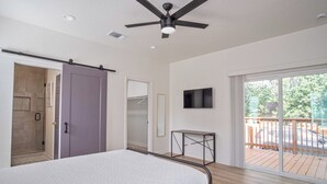 A bedroom with a bed, a ceiling fan, a TV, and a sliding door leading to a balcony. - Don't Miss Where the Fun Is 4BR/3BA Home Near DT! (San Antonio)