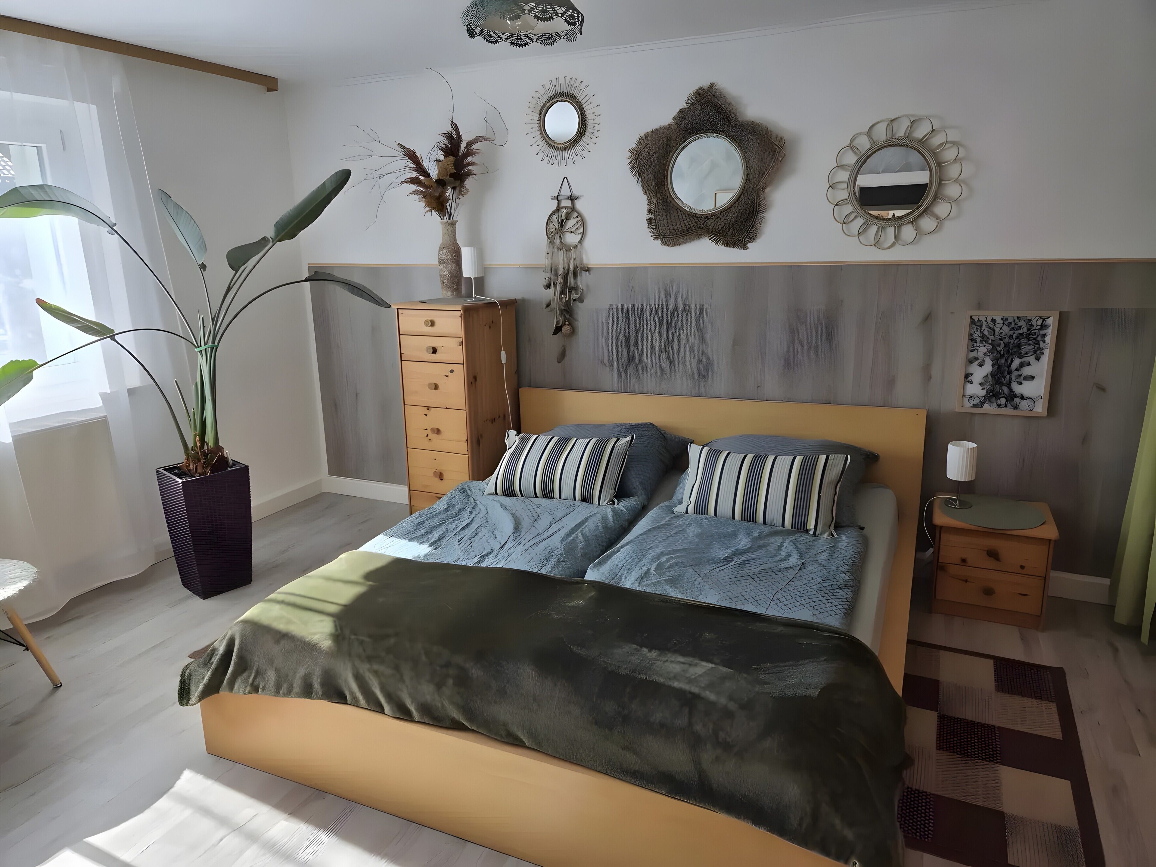 Une chambre à coucher comprenant un lit, une commode, une plante en pot, des décorations murales et une table de chevet.