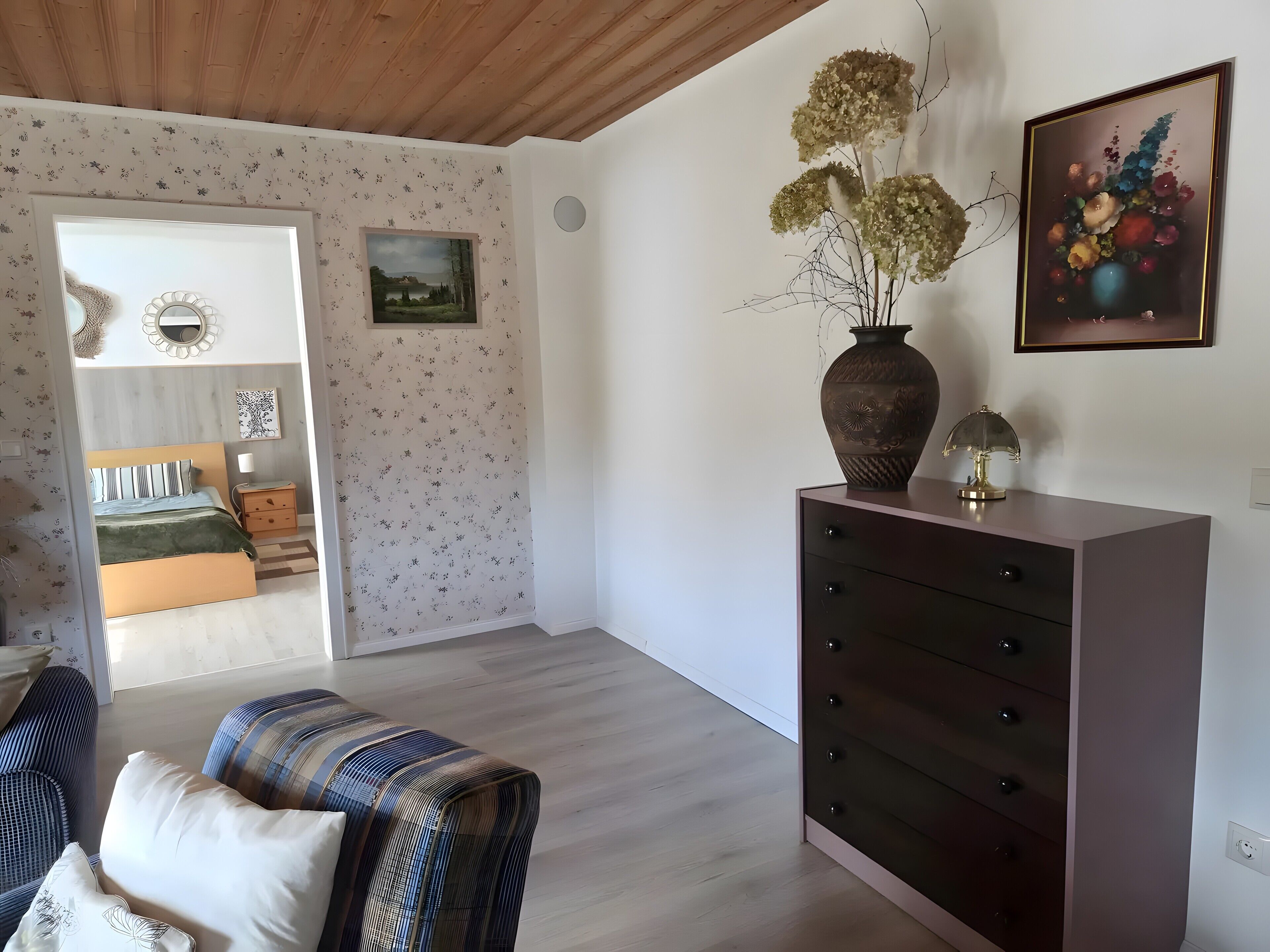 Et værelse med en seng, et skrivebord, en sofa og et maleri.