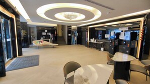 A modern hotel lobby with a central seating area, a reception desk, and a self-check-in kiosk. - Fooyee Hotel - Yizhong Branch (Taichung)
