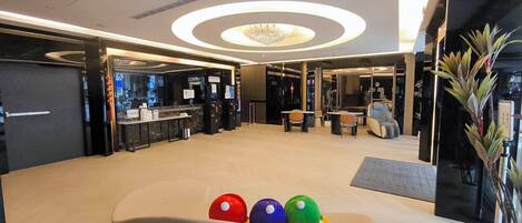 A modern lobby with a reception desk, seating area, and a chandelier.