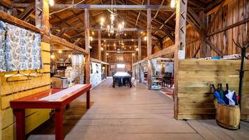 Une vaste salle avec des poutres en bois, une table centrale et une atmosphère rustique.