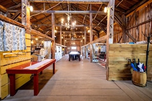 Une vaste salle avec des poutres en bois, une table centrale et une atmosphère rustique.
