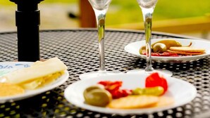 Une table avec deux verres à vin, une assiette d’olives et une tranche de fromage, ainsi qu’un gril.