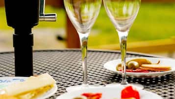 A table with two wine glasses, a plate with olives and a slice of cheese, and a grill.
