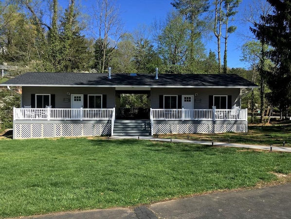 A two-story building with a front porch, a covered walkway, and a small front yard.