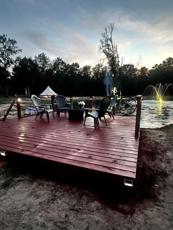Une terrasse en bois avec des meubles d’extérieur, un foyer et une fontaine.