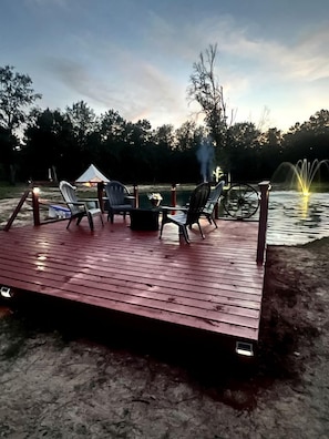 A wooden deck with outdoor furniture, a fire pit, and a fountain.