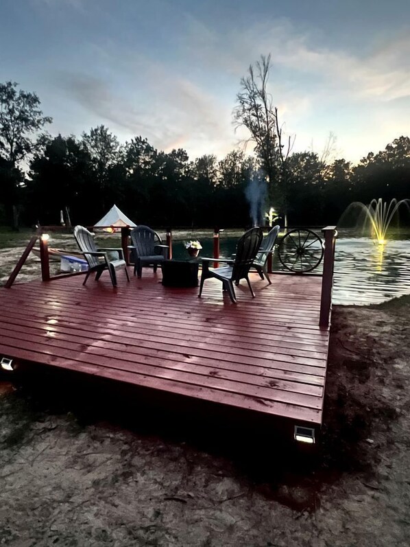 A wooden deck with outdoor furniture, a fire pit, and a fountain.