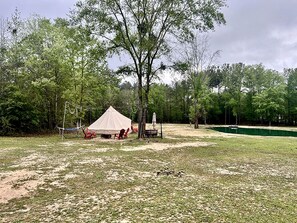 A tent set up in a grassy area with trees in the background.