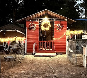 A red building with a porch, a wreath, and string lights.