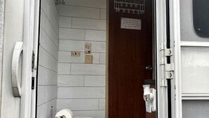 Un bagno camper compatto con un water, un piccolo cestino e un portasciugamani.