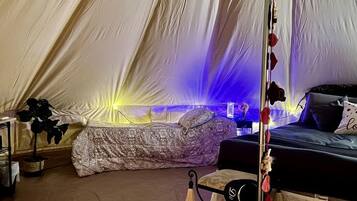 A tent with a bed, a table, and a chair.
