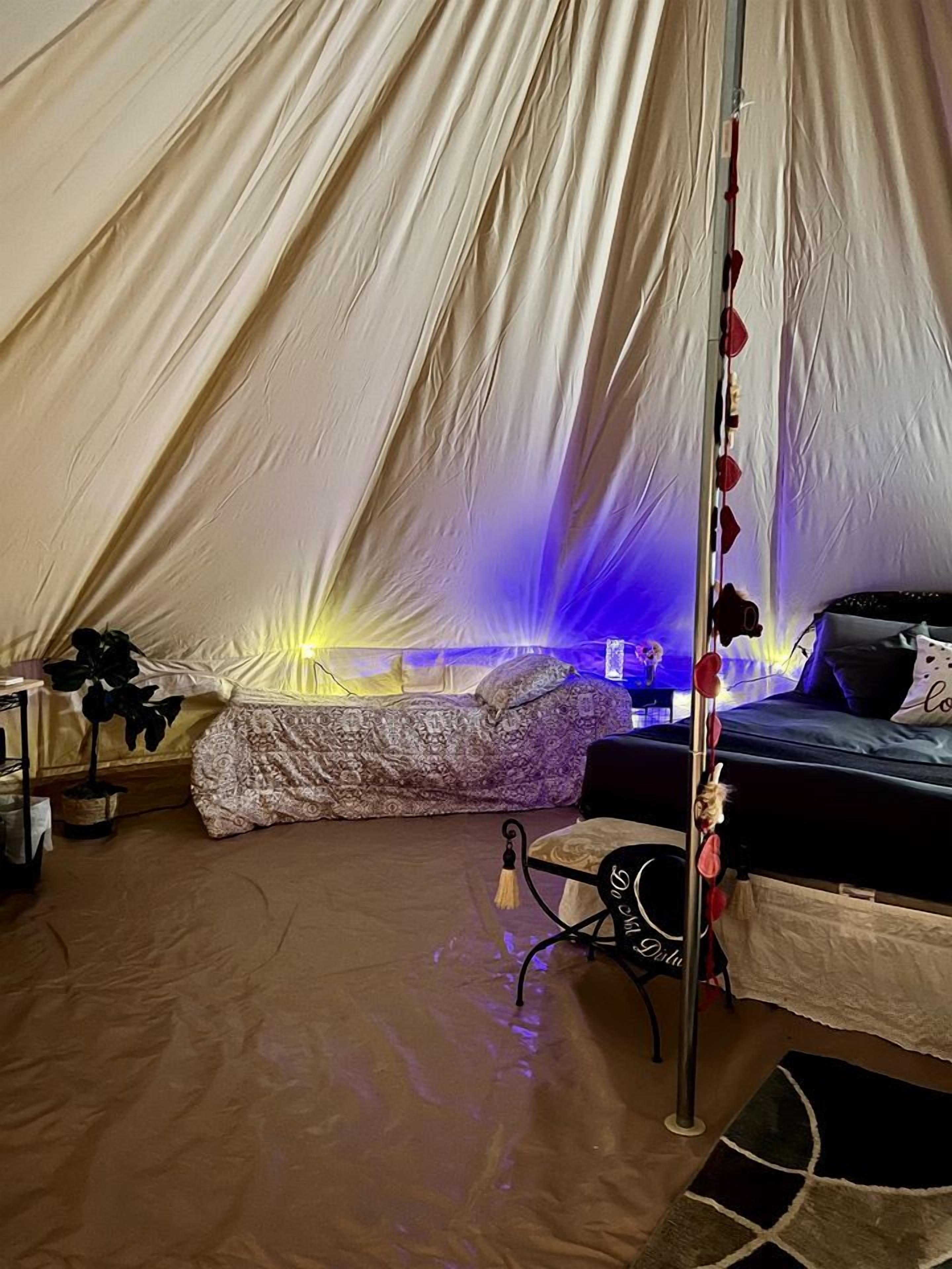 A tent with a bed, a table, and a chair.