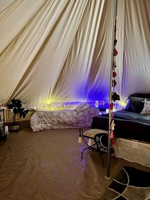 A tent with a bed, a table, and a chair. - Rustic Bell Tent on a Texan Farm, Nestled in the Sam Houston National Forest, Perfect for a Weekend Getaway (Cleveland)