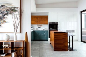 A modern kitchen with wooden cabinets, a built-in oven, and a marble countertop.