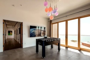 Ein modernes Interieur mit einem Kicker, einem großen Gemälde und Blick durch eine Glastür.