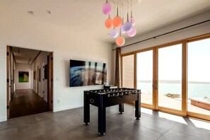 A modern interior with a foosball table, a large painting, and a view through a glass door.