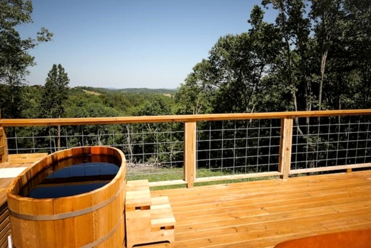 A wooden deck with a hot tub and a wooden fence.