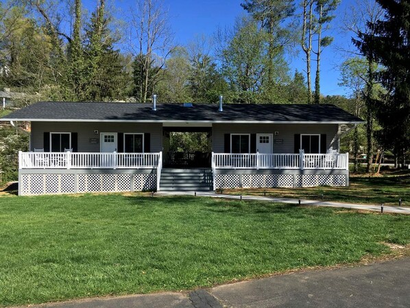 A two-story building with a front porch, a covered walkway, and a small front yard.