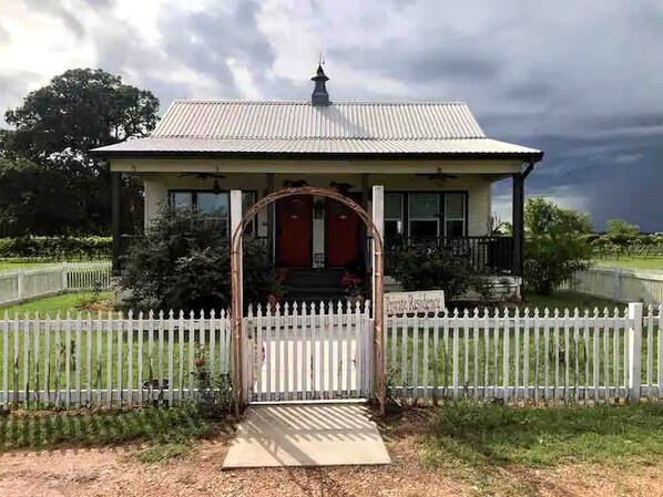 A house with a white picket fence, a covered entrance, and a metal roof.