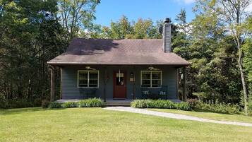 A single-story house with a front porch, a chimney, and a well-maintained lawn.