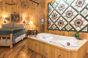 A wooden room with a bed, a bathtub, and a quilted wall hanging. - Secluded Cottage with Indoor Hot-Tub Ideal for Couples in Virginia (Lexington)