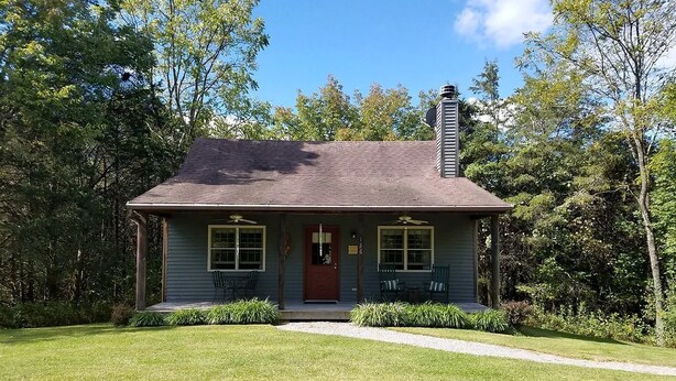 A single-story house with a front porch, a chimney, and a well-maintained lawn.