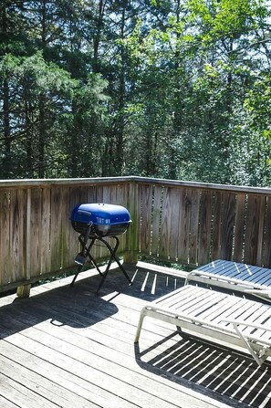 Una terraza de madera con una parrilla y una mesa de metal.