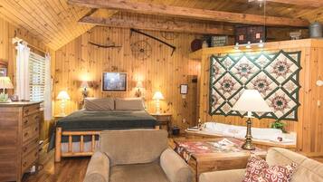 Une pièce confortable, aménagée comme un chalet, avec un lit, deux fauteuils, une commode en bois, une tapisserie murale matelassée et un panneau indiquant que des chalets sont à louer.