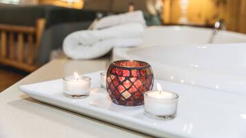 A spa area with a white bathtub, a mosaic candle holder, and two lit candles on a tray.