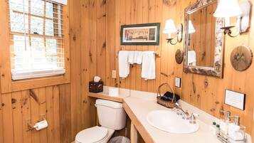 A wooden-paneled bathroom with a toilet, sink, and a framed picture on the wall.