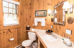 Un baño con paneles de madera, un inodoro, un lavamanos y un cuadro en la pared.