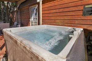 Ein Whirlpool vor einer Holzhütte, mit einem Sicherheitsschild.