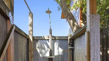 A wooden deck with a metal railing, a hanging light fixture, and a wooden fence in the background.