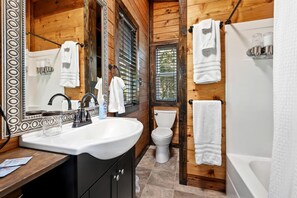Baño de cabaña de madera con lavabo, inodoro y bañera.