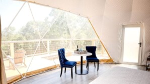 Una habitación con tienda de campaña, una mesa, sillas, una puerta y vistas al exterior.
