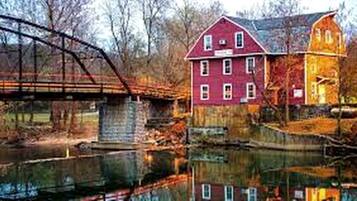 Un bâtiment rouge avec une tour, un pont et une étendue d’eau paisible.