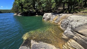 Un paysage naturel caractérisé par un plan d’eau aux eaux claires, des formations rocheuses et une végétation luxuriante.