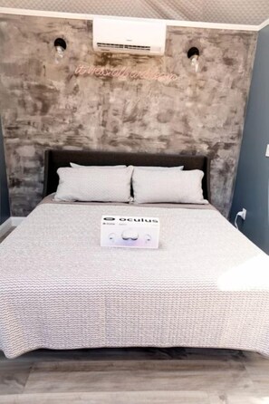 Een bed met een grijs hoofdbord met textuur, twee kussens en een witte spreideken.
