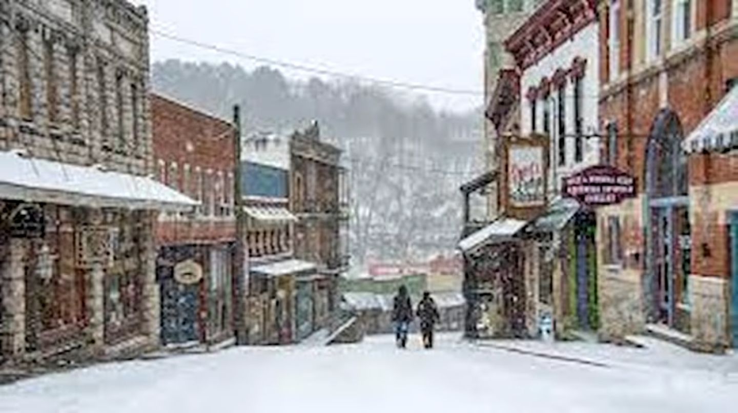A historic town street with buildings, a signboard, and a person walking.
