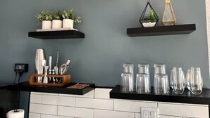 A kitchen with a black countertop, hanging light fixtures, and decorative items on shelves.