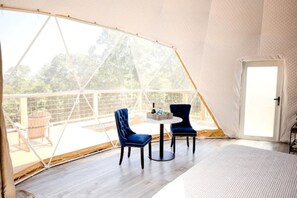 Une pièce aménagée avec une tente, comprenant une table, des chaises, une porte et donnant sur l’extérieur.