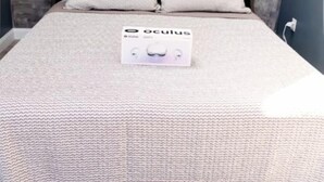 A bed with a grey textured headboard, two pillows, and a white bedspread.